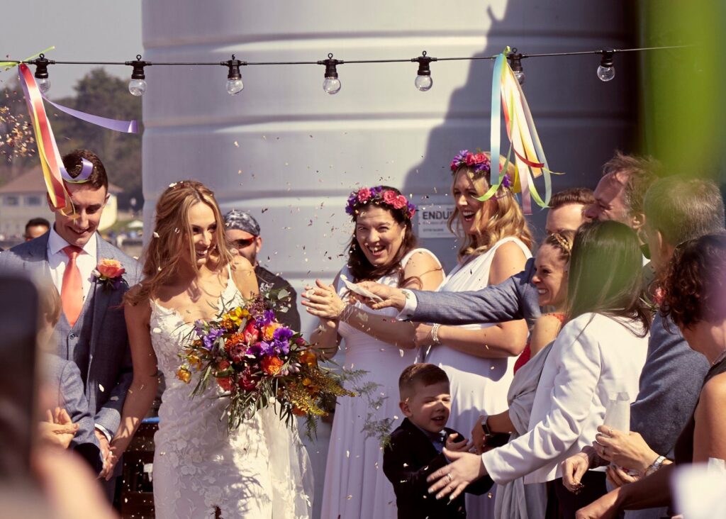 Bridesmaids throwing confetti at the newly weds. Outside in the sun on the beach front at Whitstable Kent