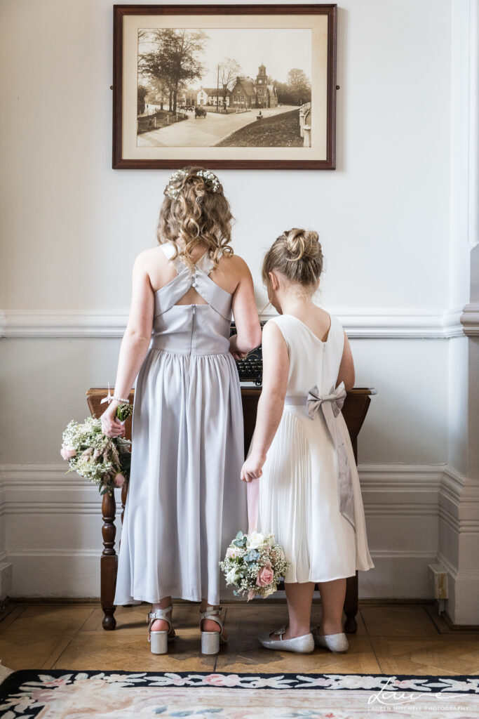 Bridesmaid and flower girl sneeking some treats before doing their duties. Facing away from camera